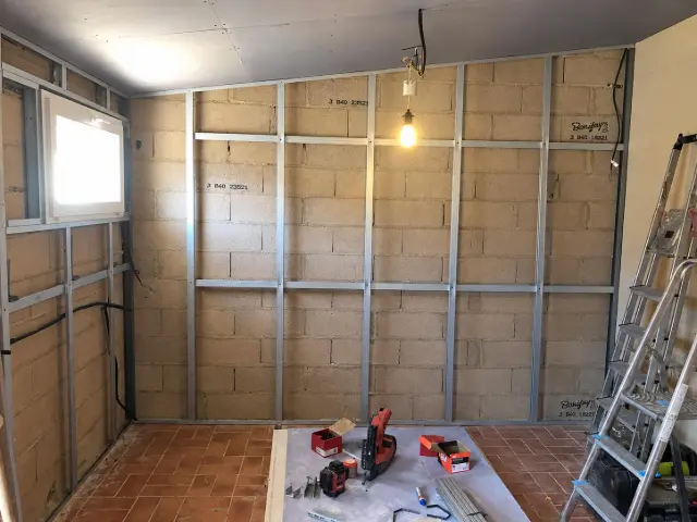 Ossature métallique fixée sur un mur en parpaing avant la pose du doublage
