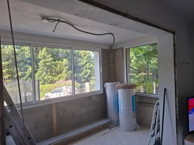 La même pièce avant travaux : murs en parpaing et rouleaux d'isolant prêts à poser